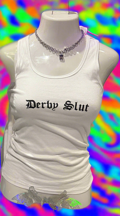 Mannequin wearing a white shirtwith 'Derpy Slut' text, surrounded by colorful items on a reflective surface.